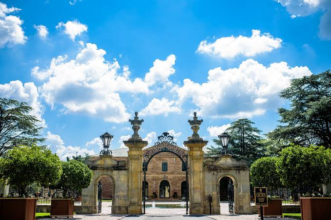 Jasna Polana’s ornate entrance gates beneath a bright blue sky
