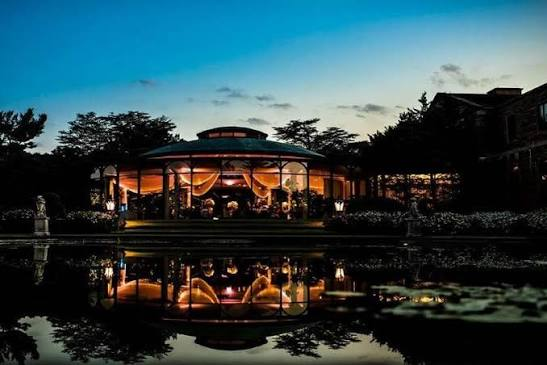 Jasna Polana’s illuminated pavilion reflected in the water at dusk